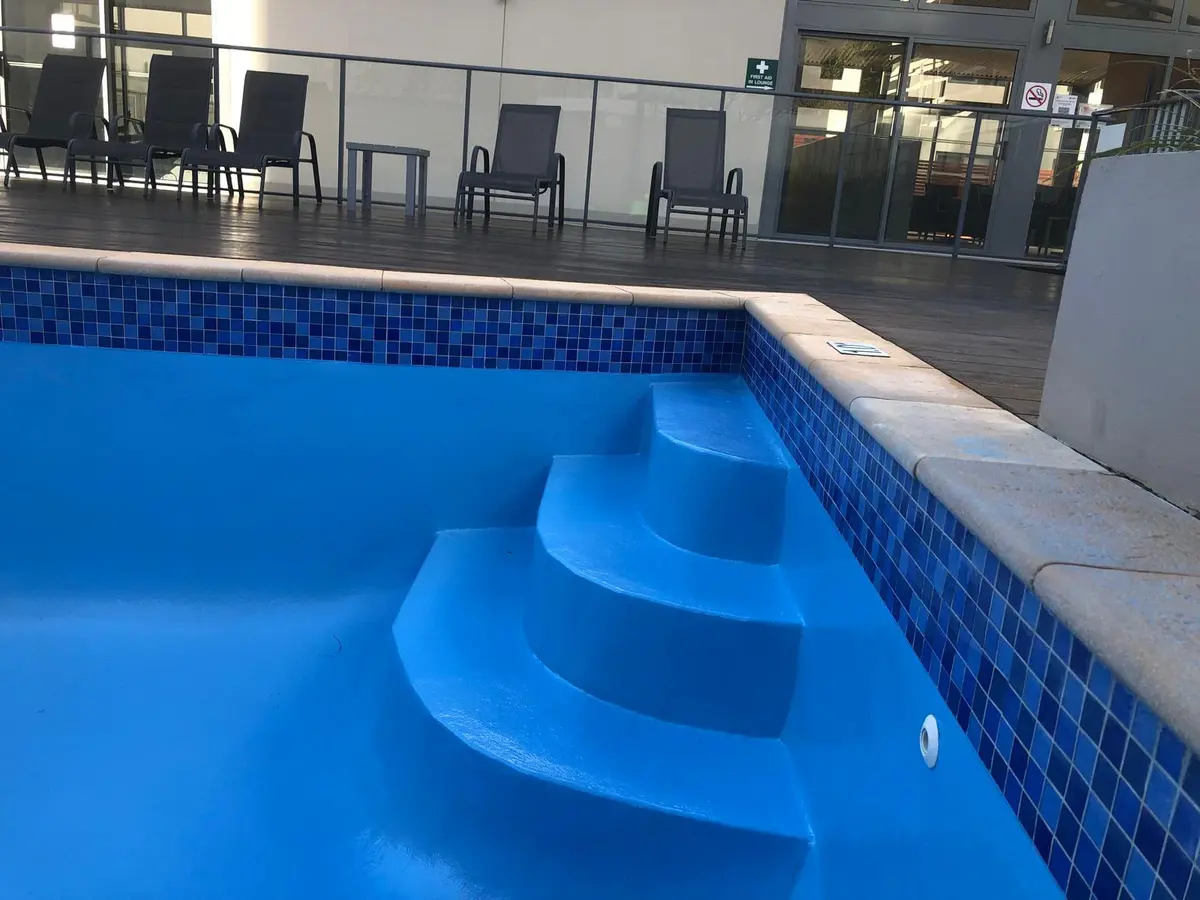 Finished blue fibreglass pool steps beside mosaic waterline tiles